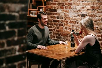 A man and a woman are sitting at a table drinking wine.