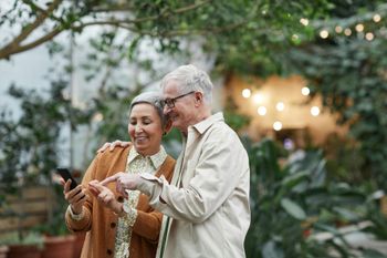 An elderly couple is looking at a cell phone together.
