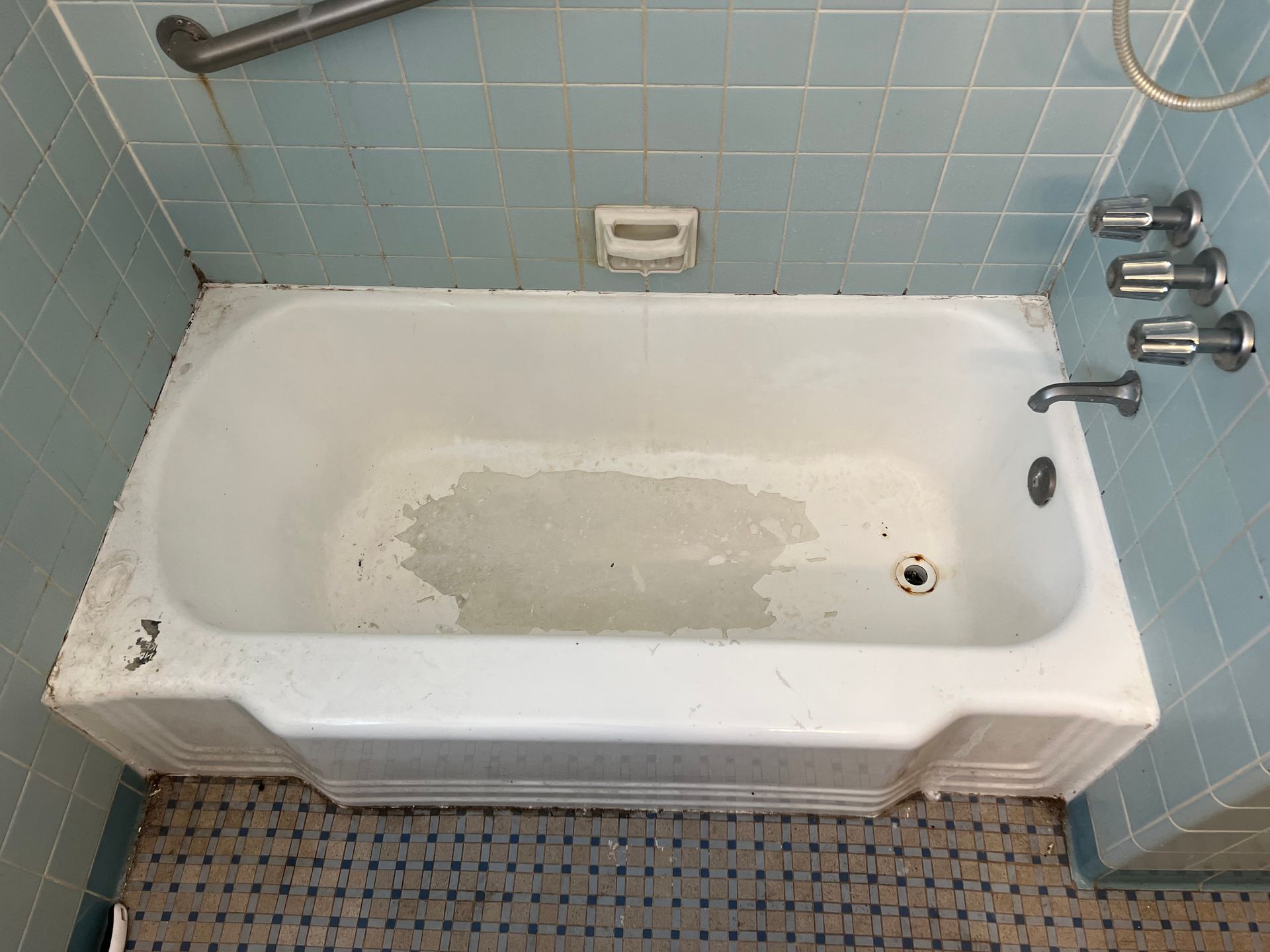 An Empty Bathtub in A Bathroom with Blue Tiles — Inverness, FL — First Class Refinishing 