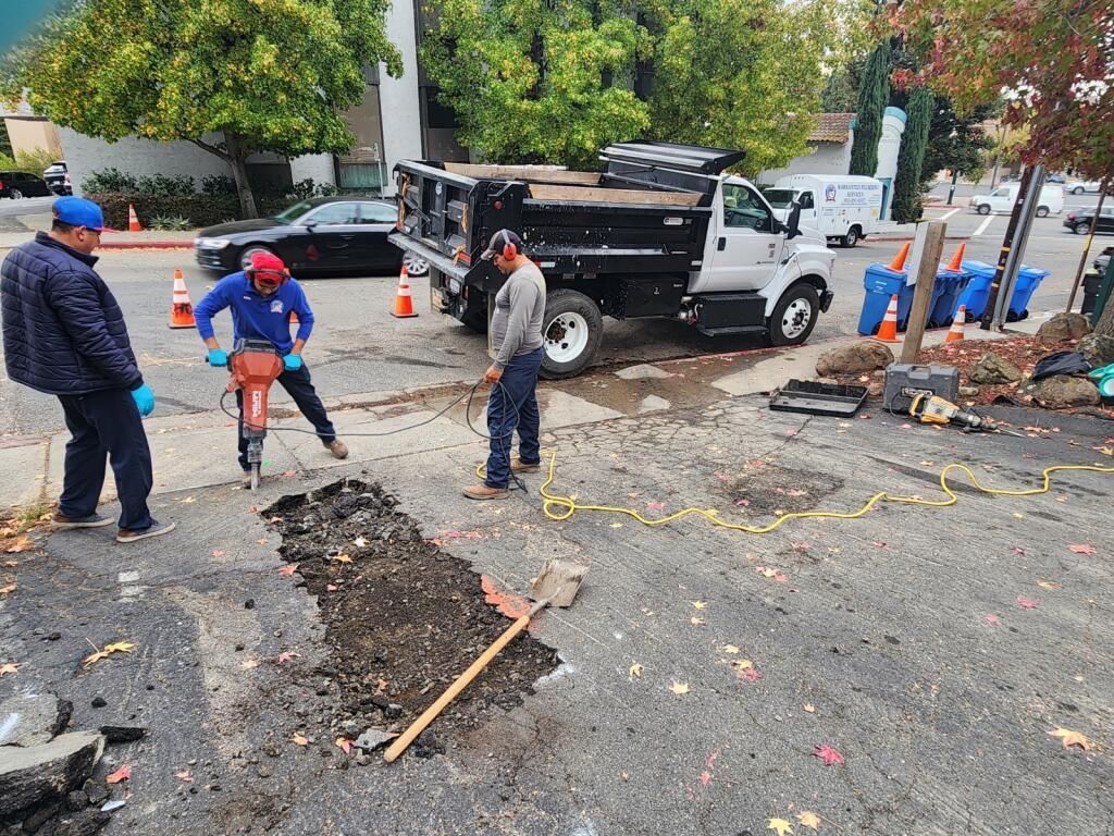 a man is using a drill to dig a hole in the ground — Concord, CA — Warranted Plumbing Services Inc.