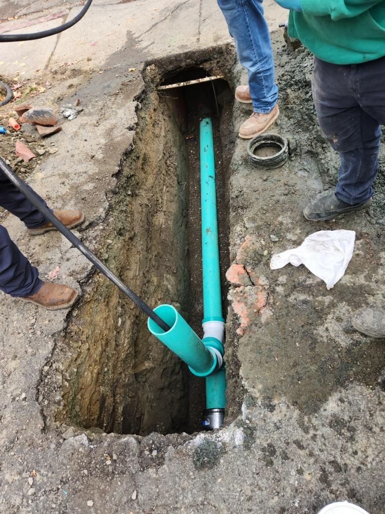 a green pipe is being installed in a hole in the ground — Concord, CA — Warranted Plumbing Services Inc.