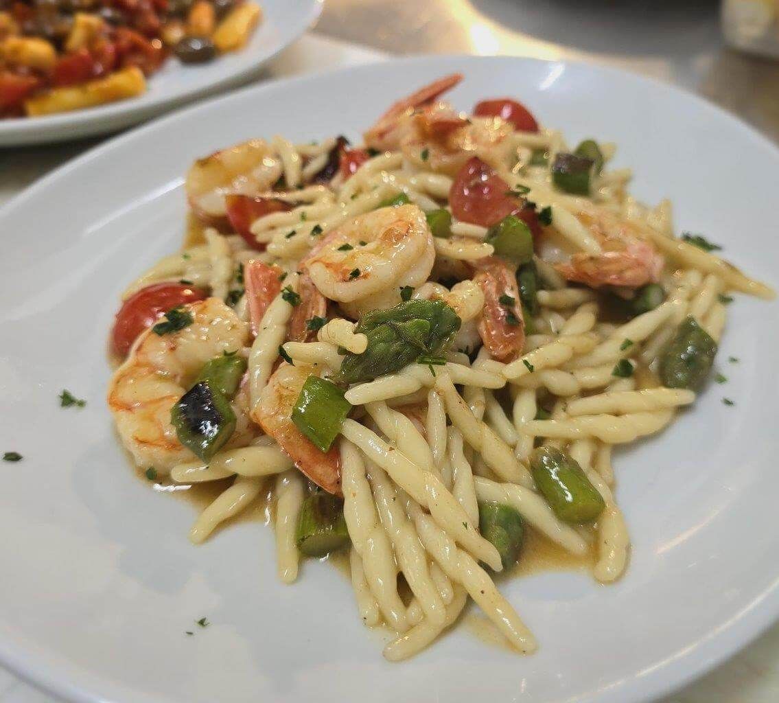 Un piatto bianco con sopra spaghetti e vongole su un tavolo.