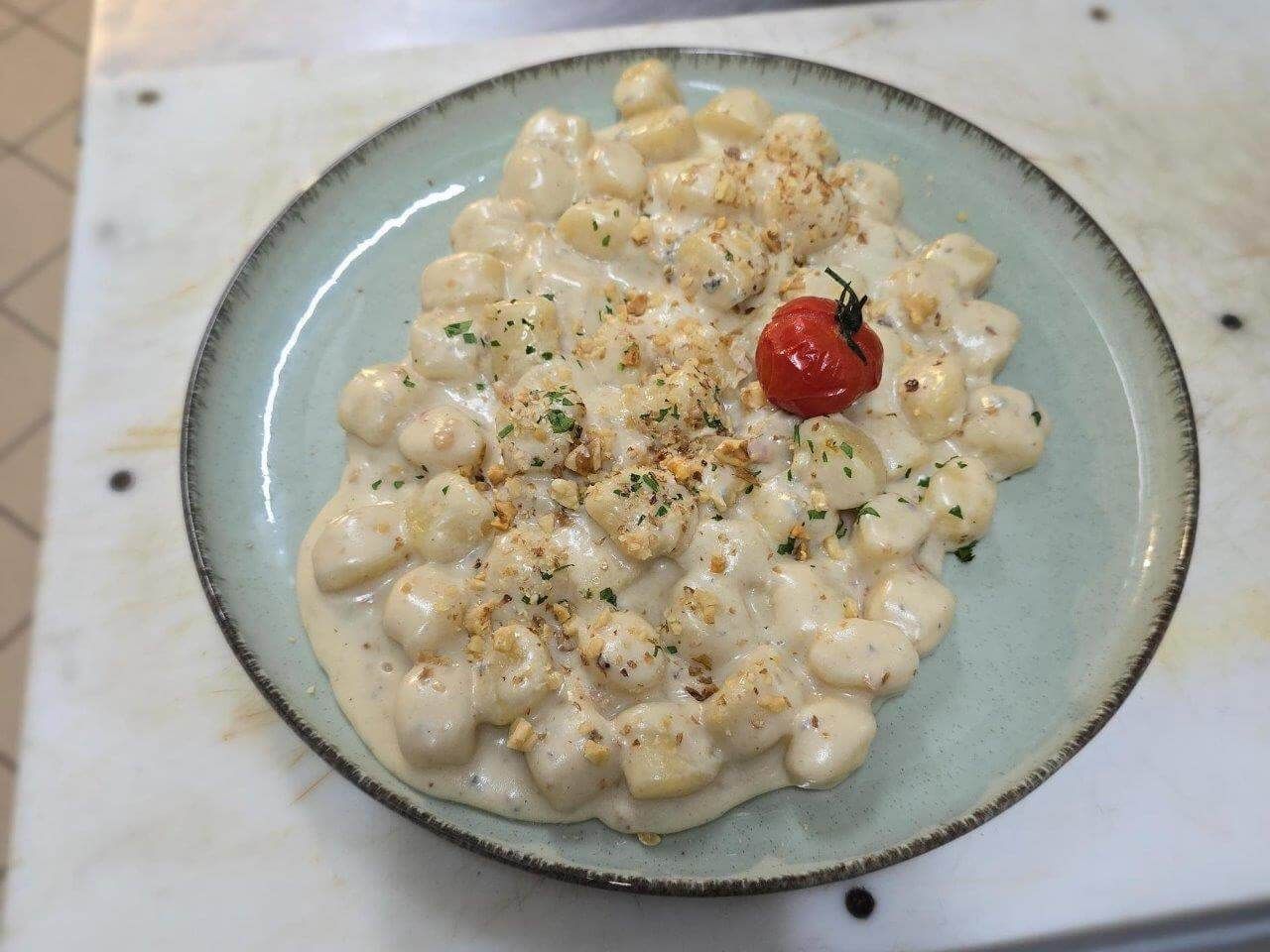 Un piatto di gnocchi al basilico su un tavolo di legno.