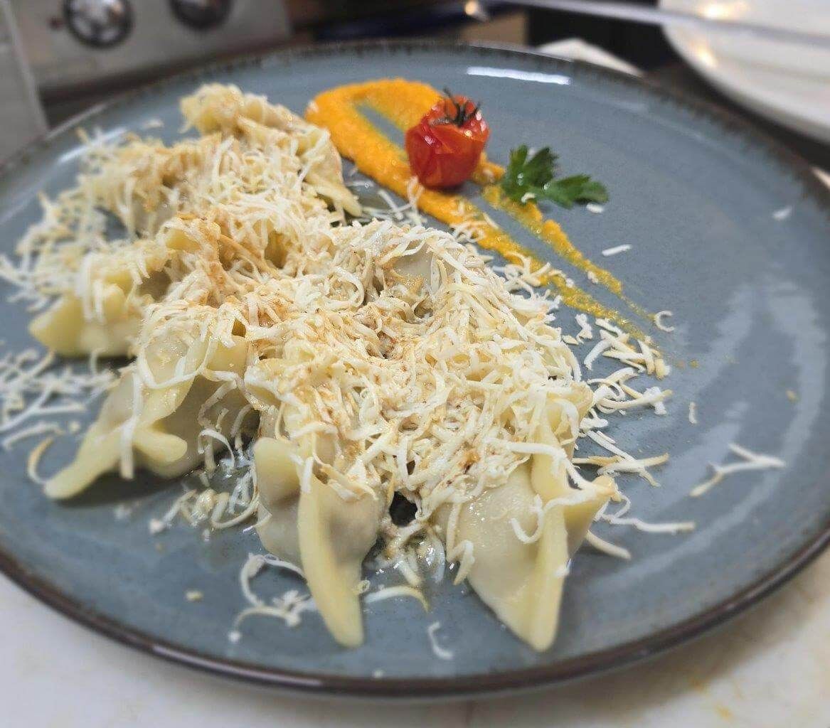 Una ciotola bianca piena di tagliatelle e salsa su un tavolo.