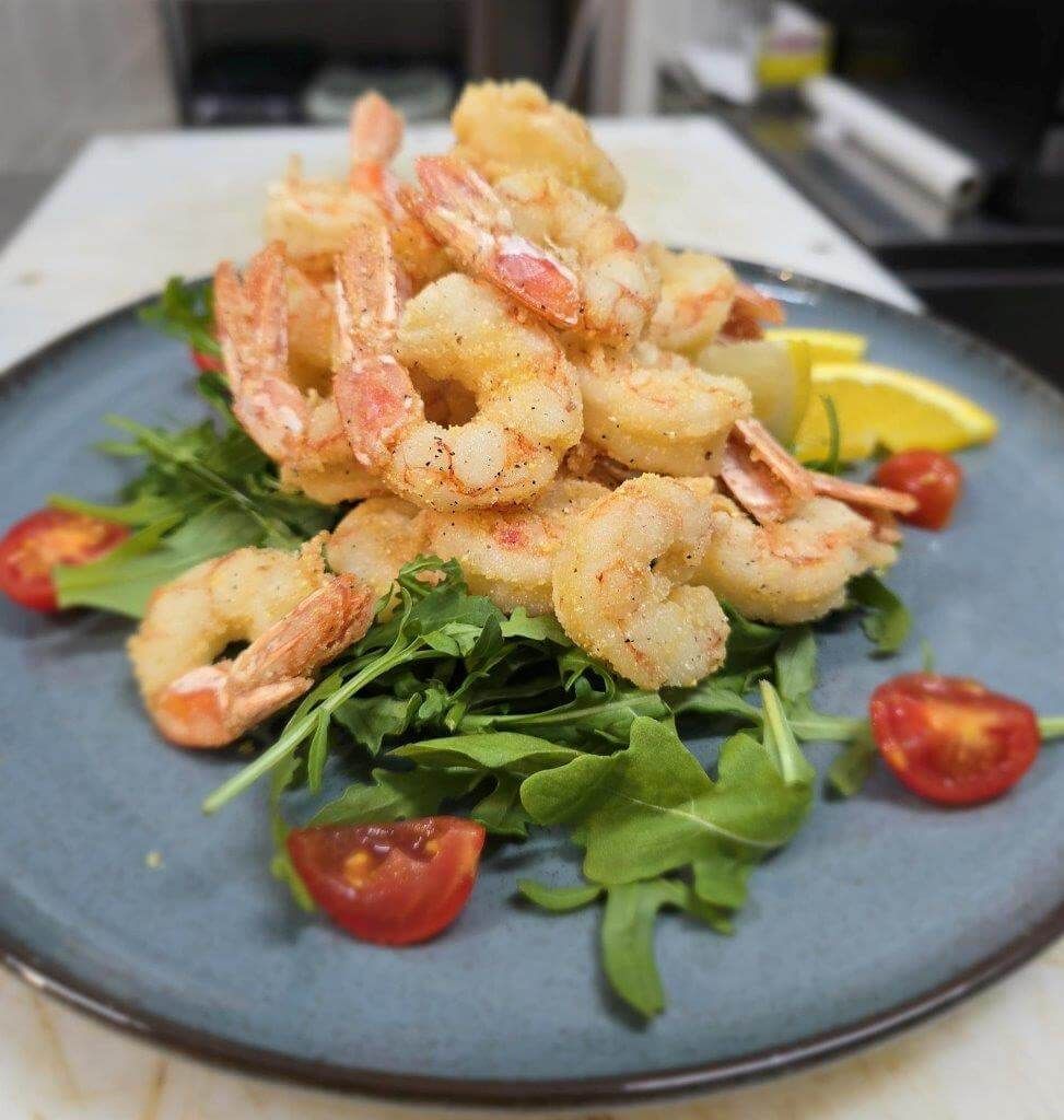 Un piatto bianco con sopra pesce e fette di limone