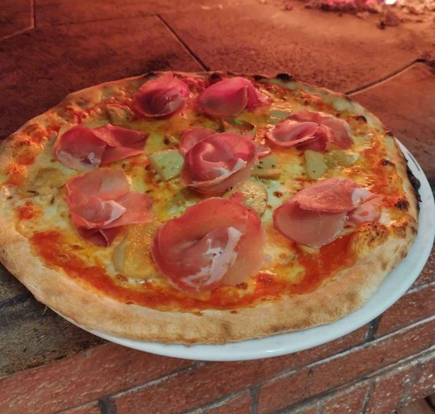 Una pizza con prosciutto e ananas su un piatto bianco