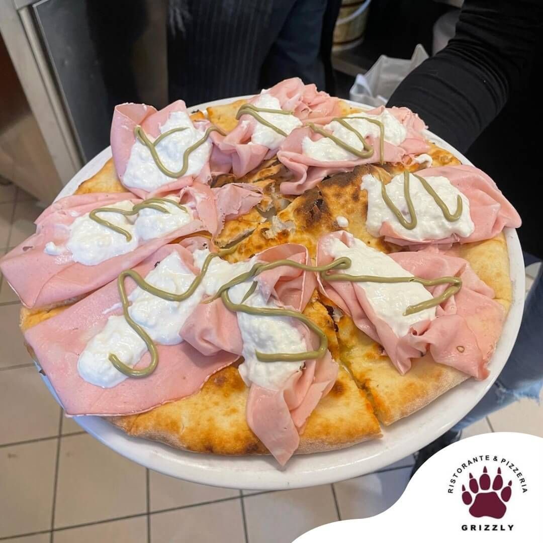 Una persona tiene in mano un piatto bianco con una pizza sopra