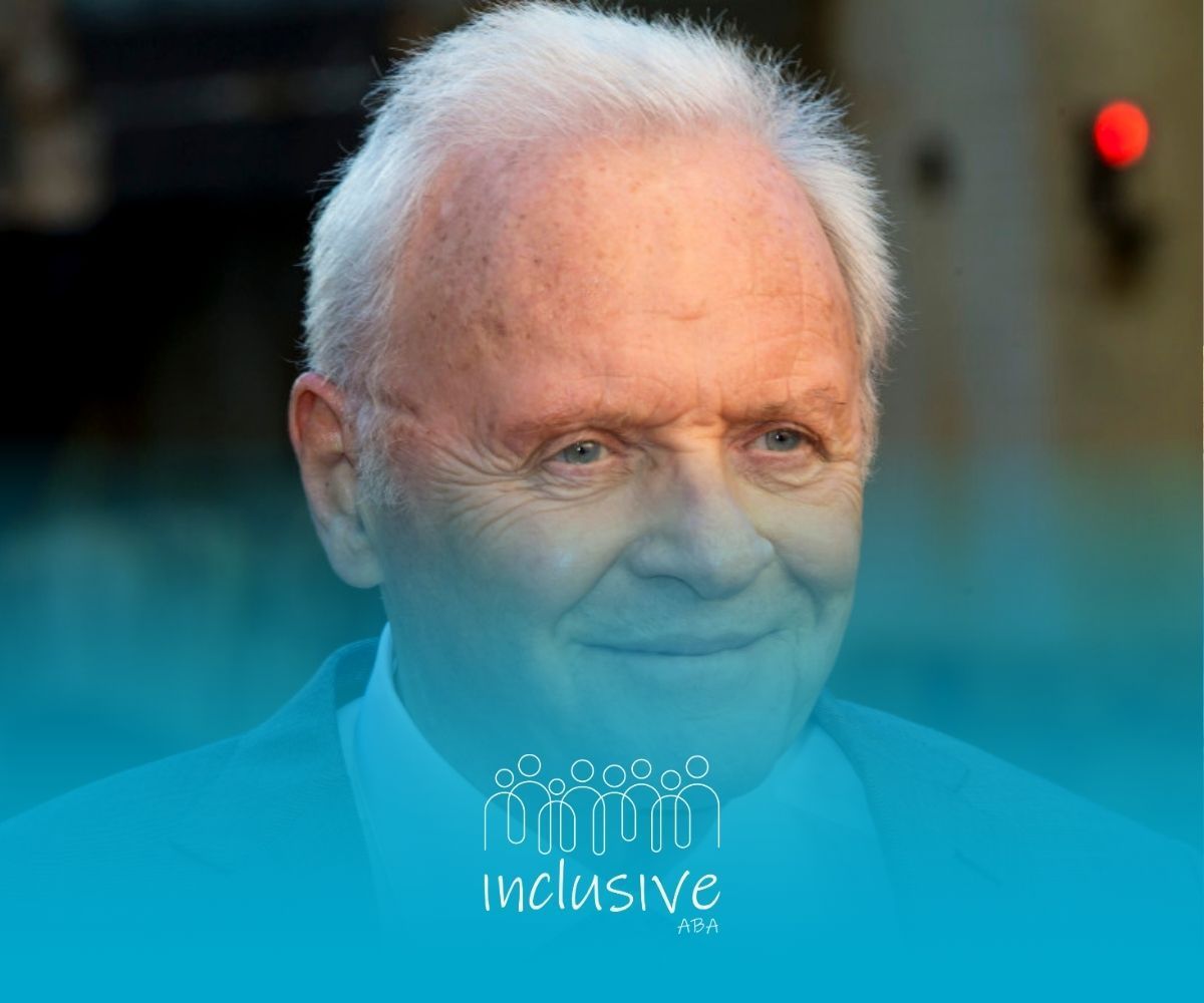 Anthony Hopkins, a famous actor diagnosed with autism, in a suit smiling at an outdoor event in NE.