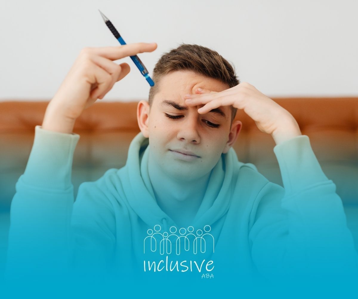 Teenager with pen to head, looking stressed, indoors.