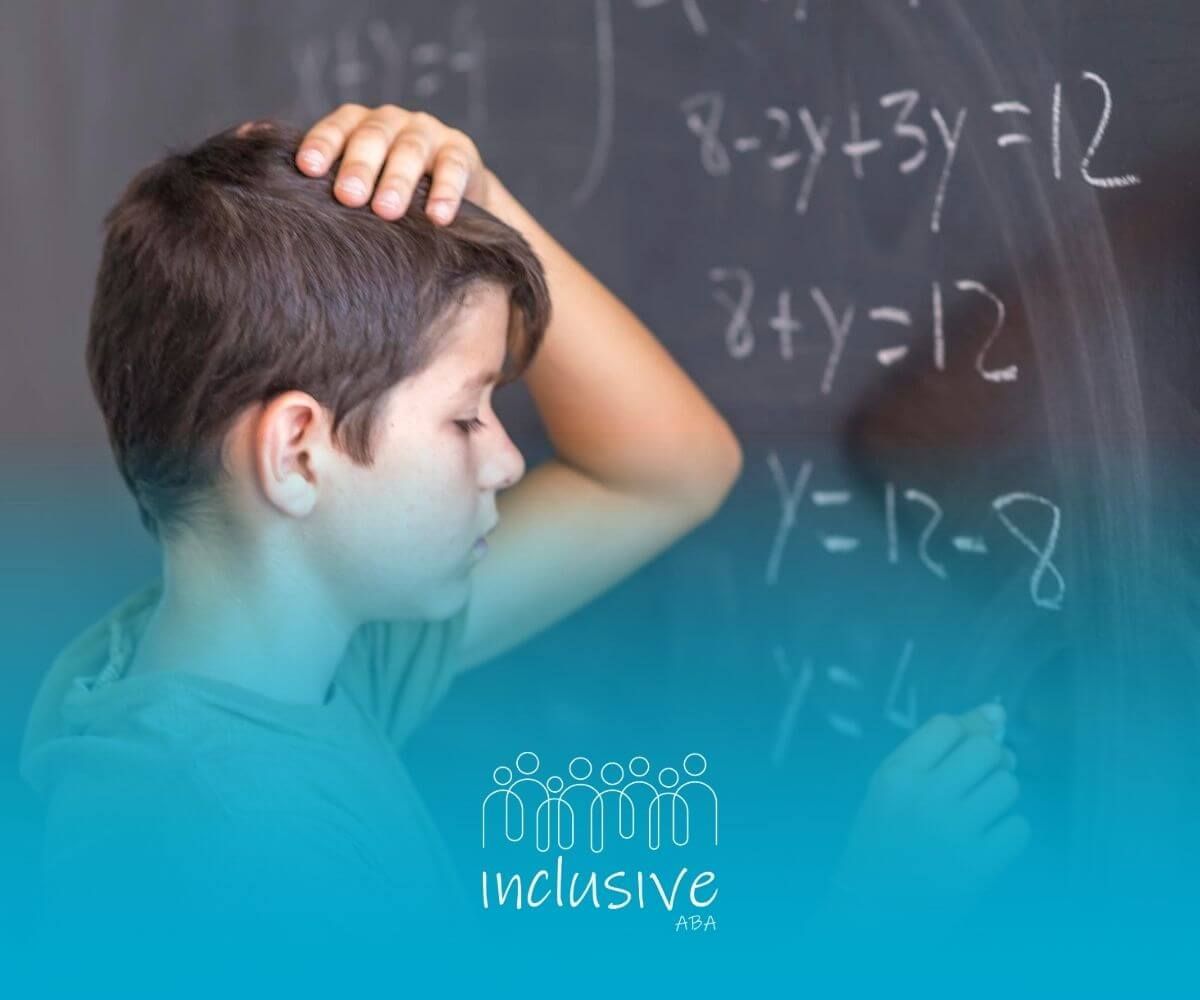 Boy with autism solving math equations on chalkboard.
