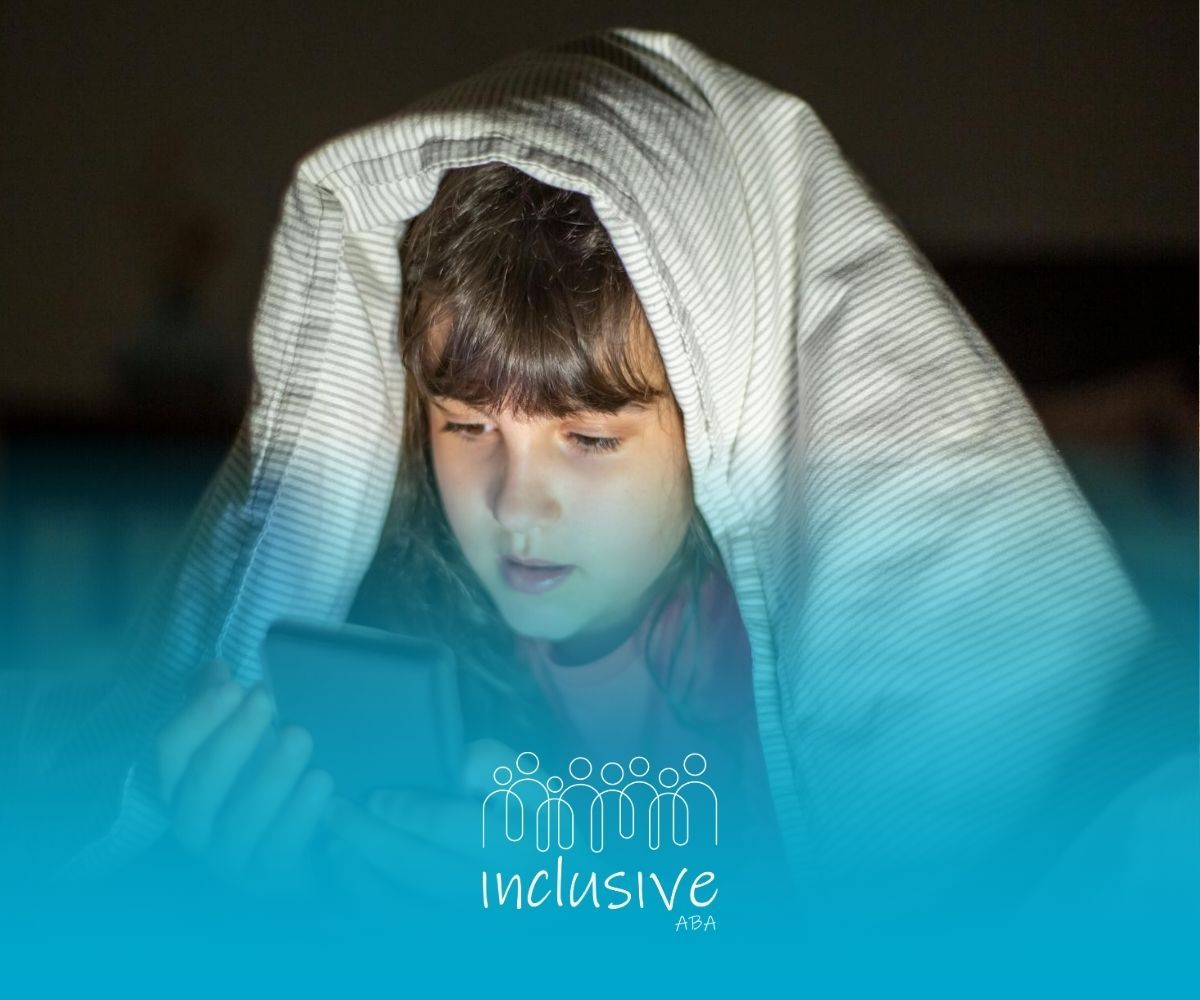 An autistic child using phone under a blanket at night in a dimly lit room after ABA therapy in CO.