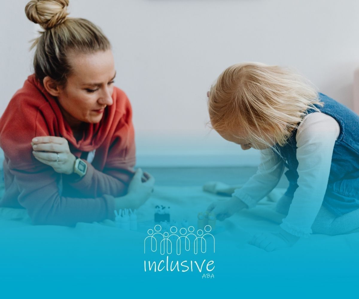 A person in a red hoodie plays on the floor with a young child. The image features the inclusive logo and branding.