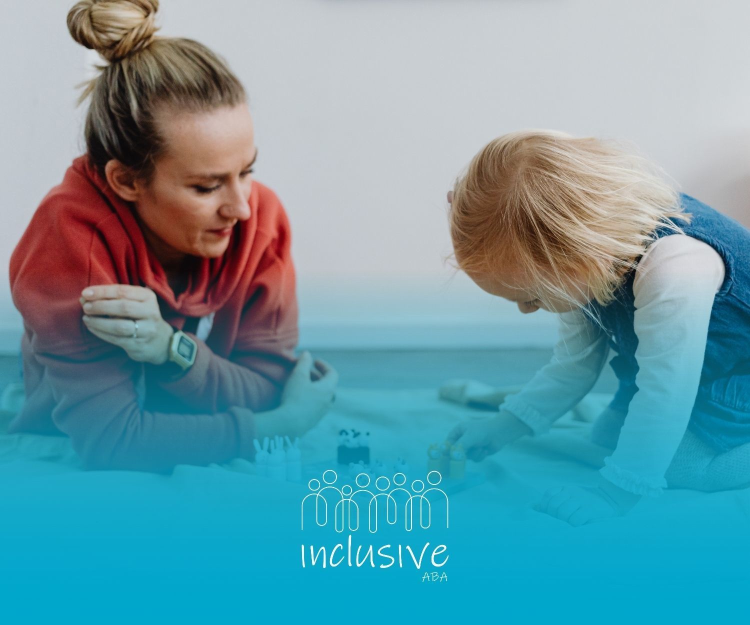 Woman in red hoodie and child playing together on the floor.