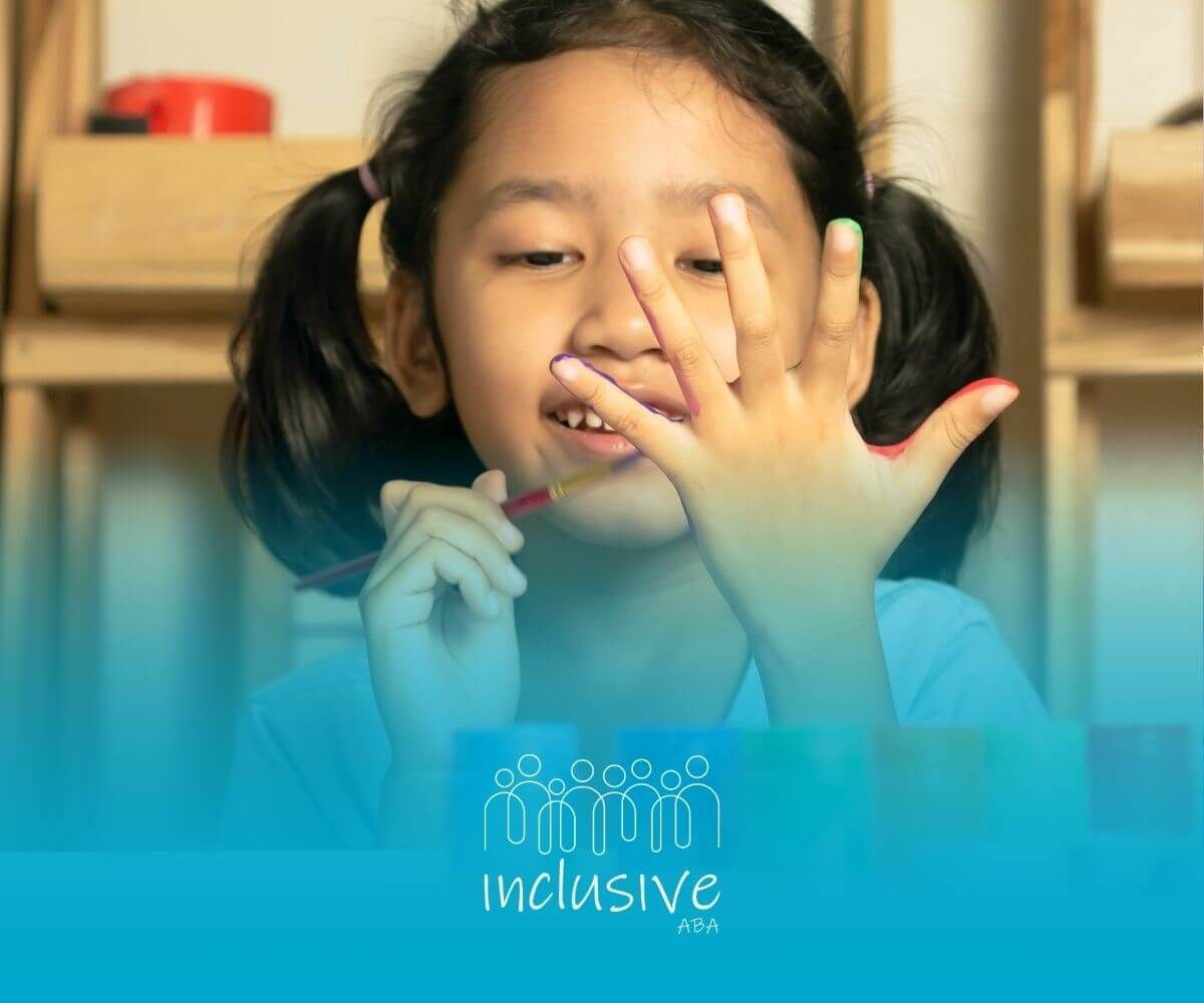 A little girl with autism is sitting at a table painting her nails in ABA therapy.