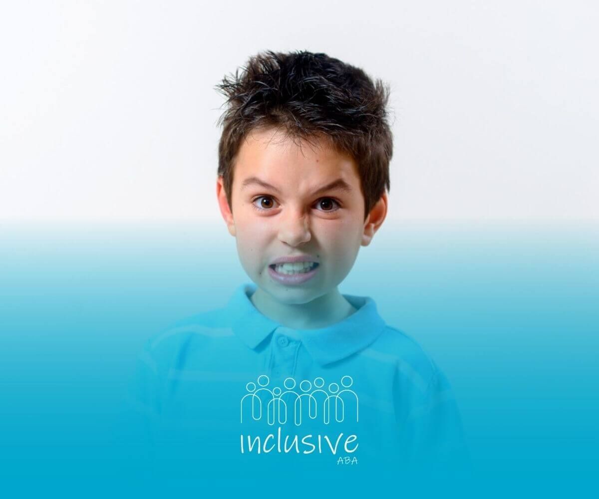 A boy with autism shows a frustrated expression, baring his teeth.