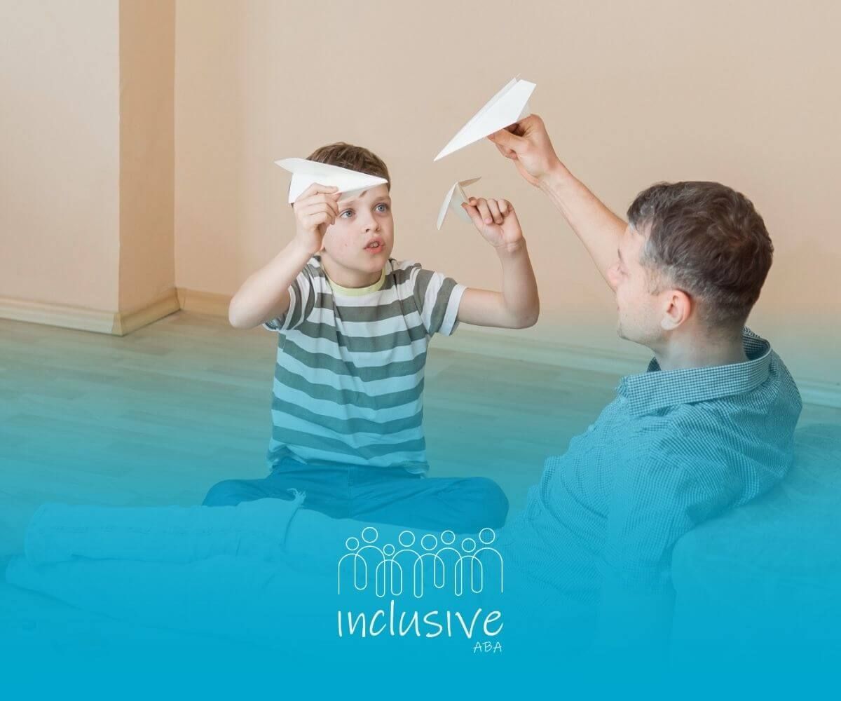 BCBA and boy with autism playing with paper airplanes on the floor.