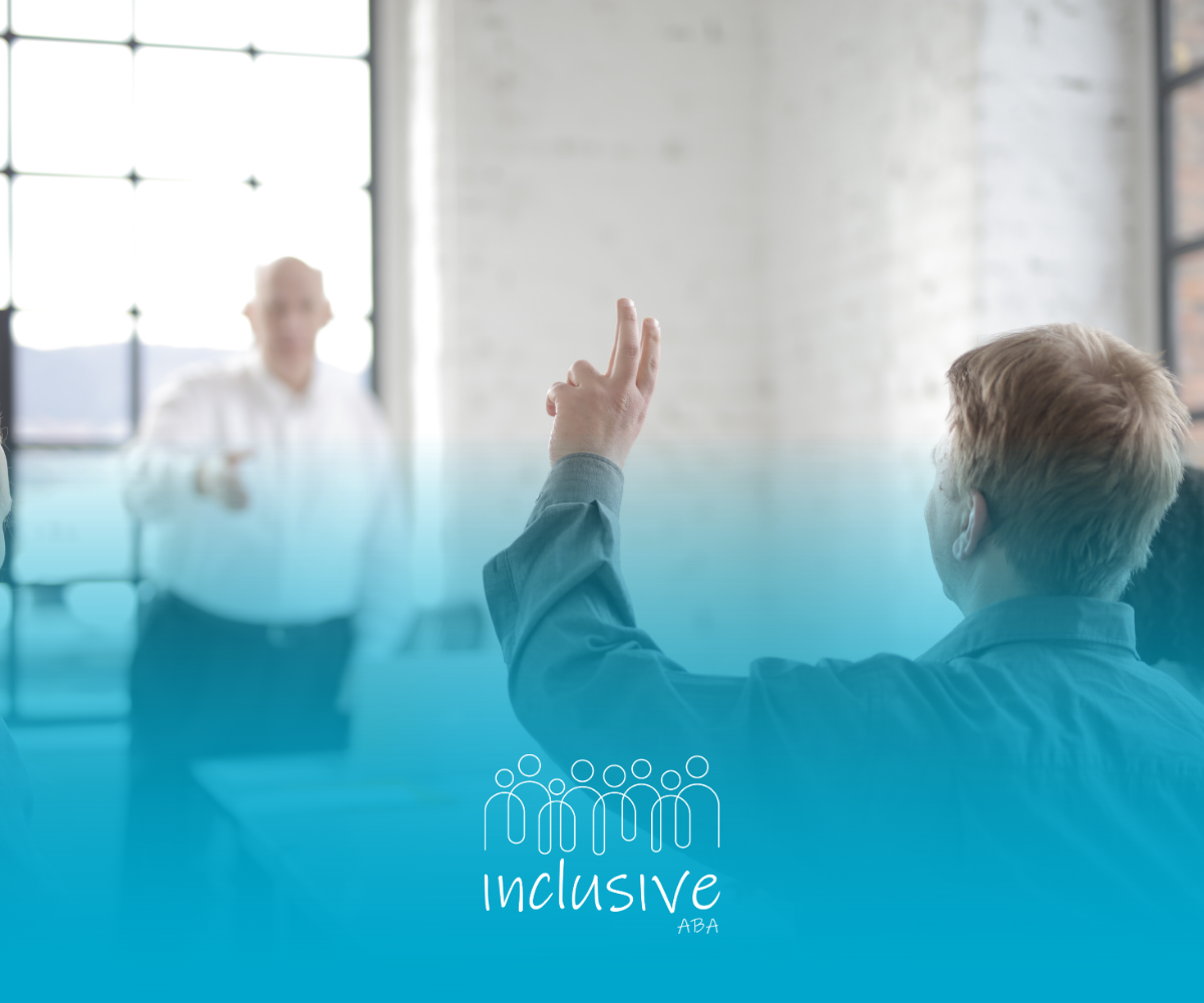 A person raising their hand to ask a question in a meeting. Instructor in background.