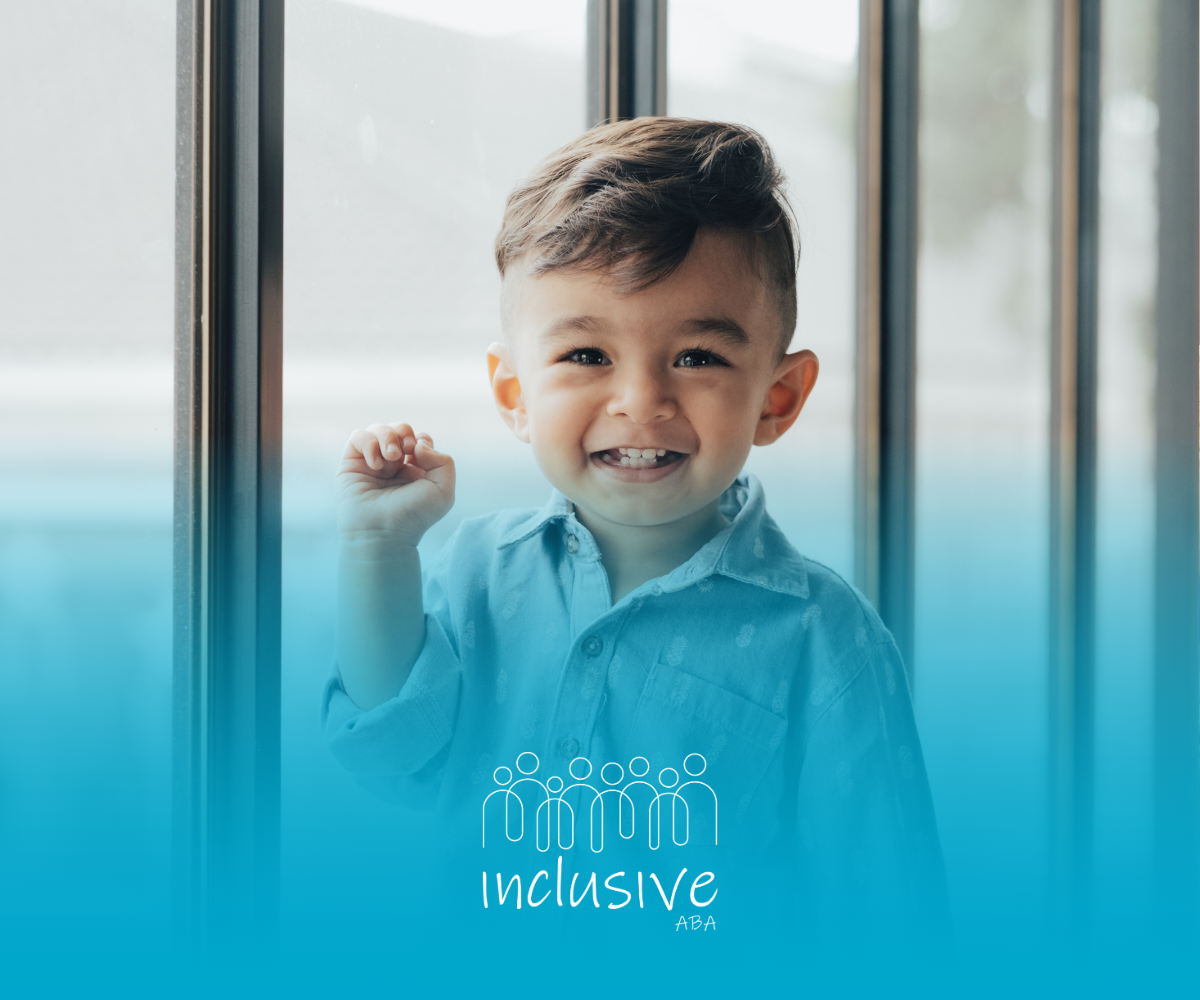 A young boy is standing in front of a window and smiling.