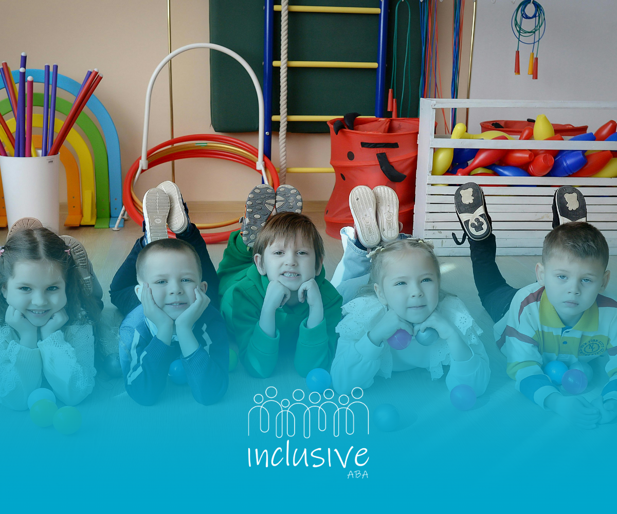 Five children lie on their stomachs in a room with colorful gym equipment, posing for a photo. Logo reads 