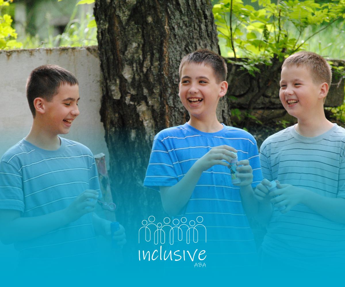 Three boys laughing outdoors, near a tree. One holds a bubble wand. Blue tones.