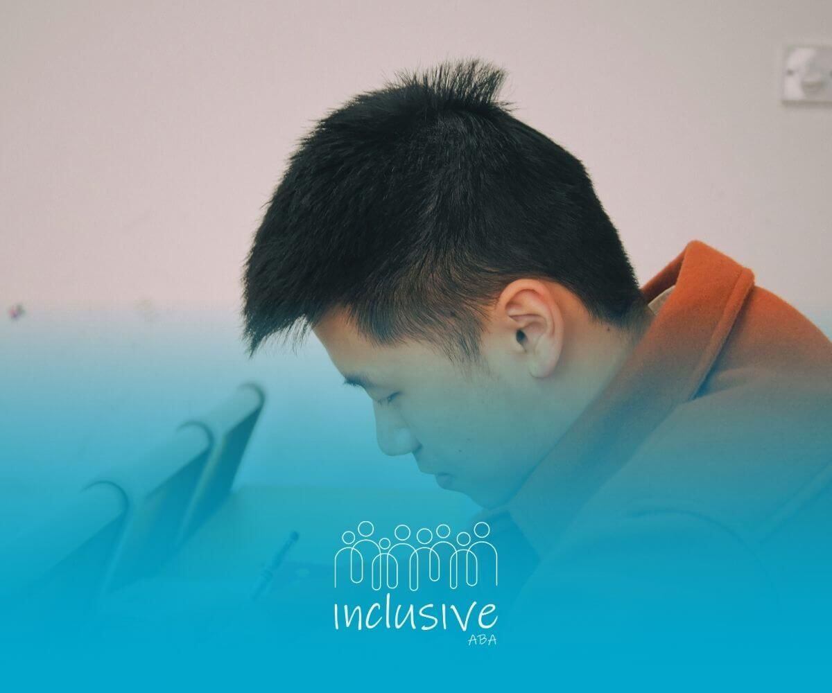 A BCBA student sits in a classroom, focused as he studies and writes notes during a quiet lesson.