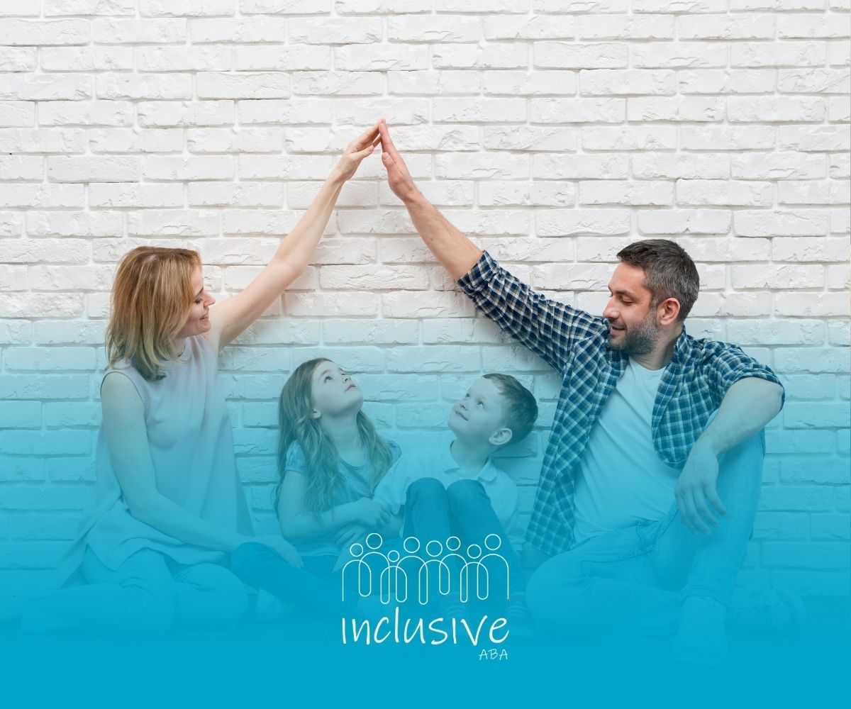Family of four making a roof shape with their hands. Sitting in front of a white brick wall.