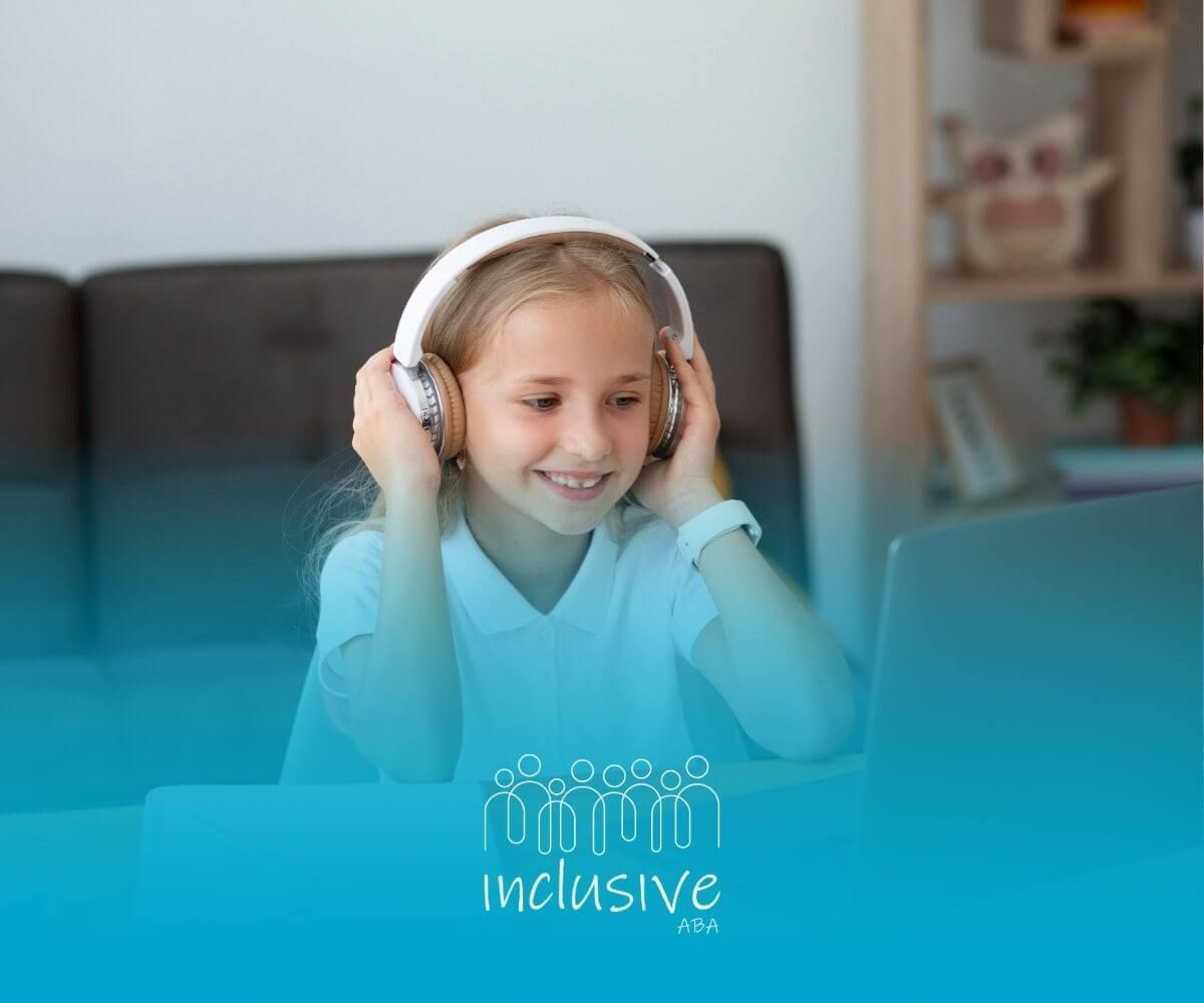A young girl wearing headphones is joining remote ABA therapy on her laptop.
