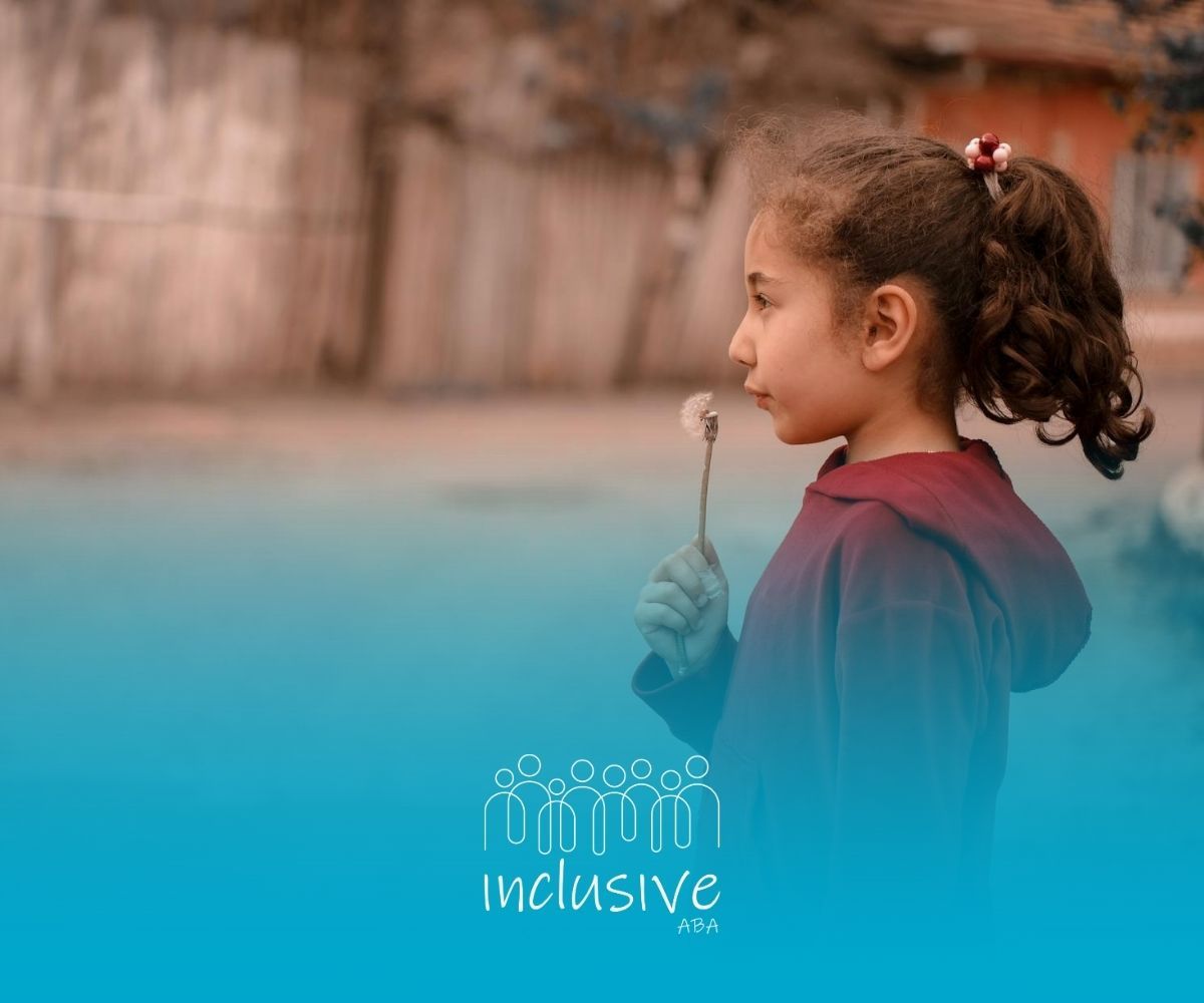 An autistic girl in red hoodie holding dandelion outdoors during ABa therapy session in Nevada.