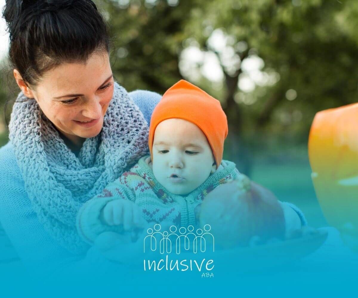 A BCBA and baby with autism enjoy autumn activities with pumpkins outdoors.