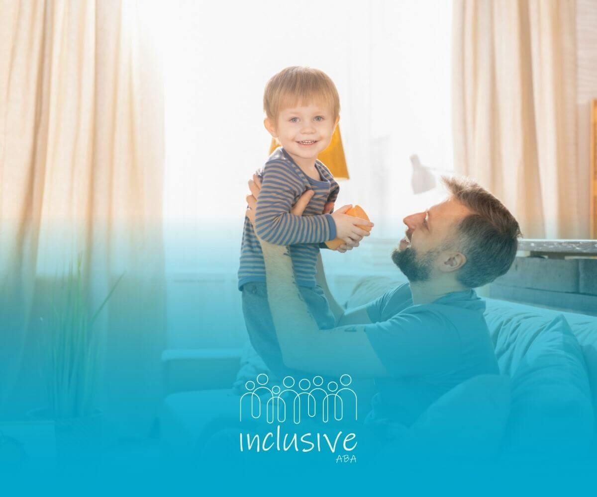 Father holding a smiling toddler with autism who is holding an orange.