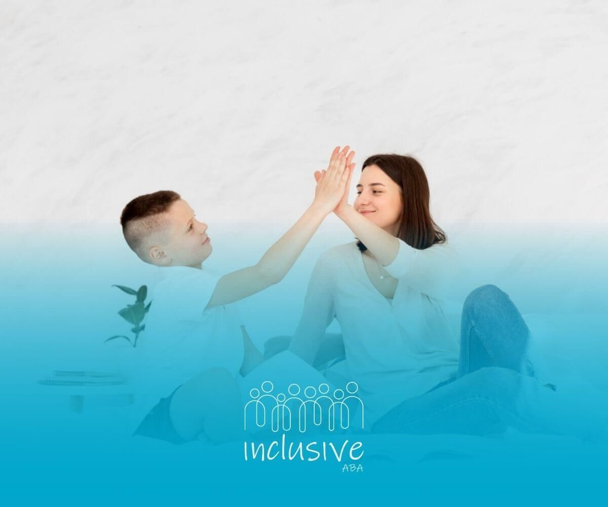 BCBA and boy with autism giving each other a high-five while studying on a bed.