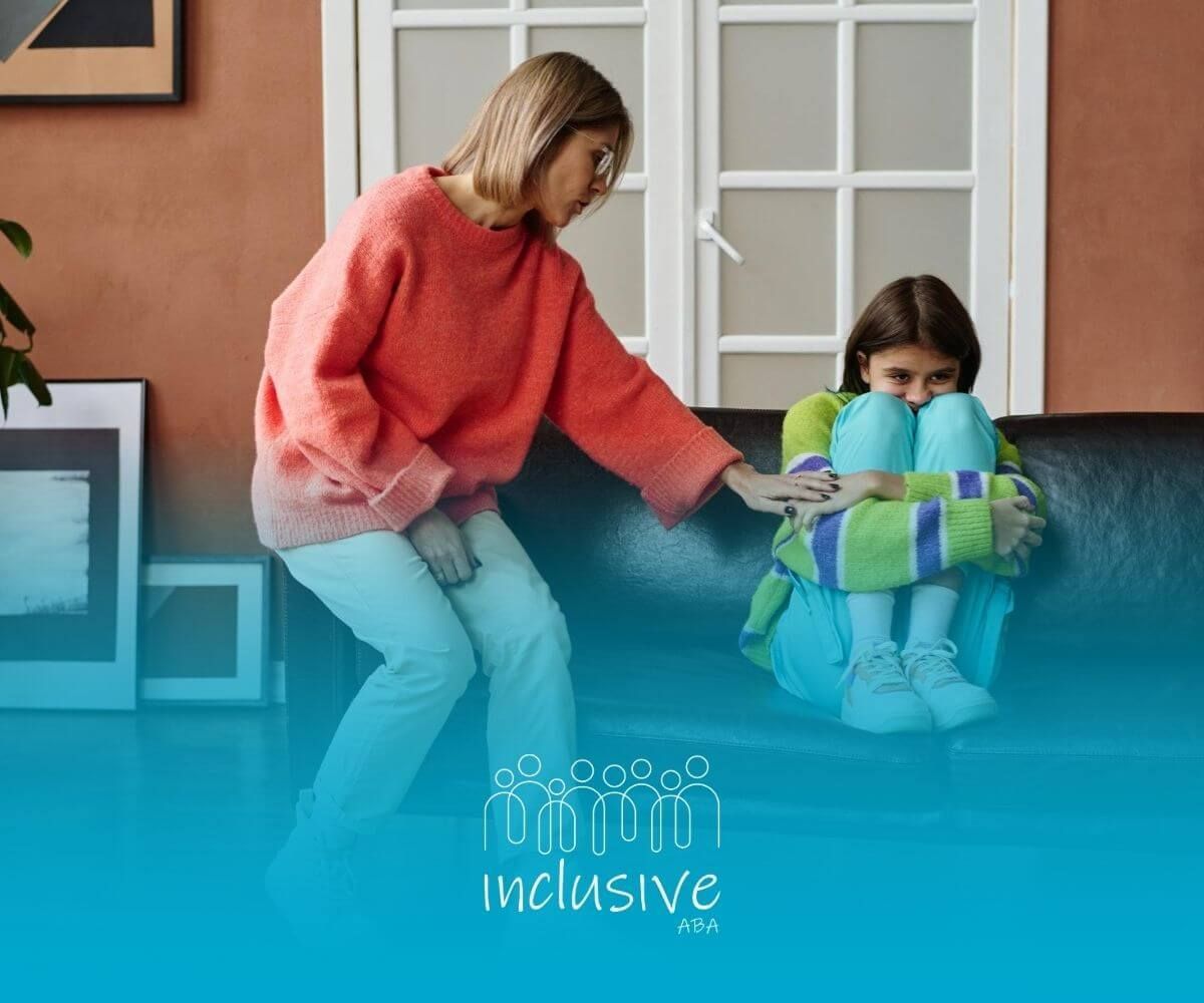 BCBA comforting a sad girl with autism sitting curled up on a couch.
