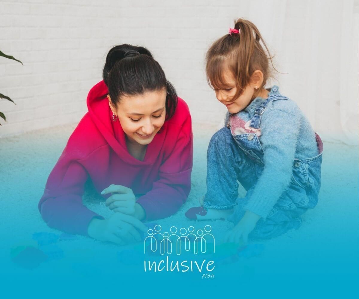 An and a little girl are sitting on the floor playing with toys.An ABA therapist and a