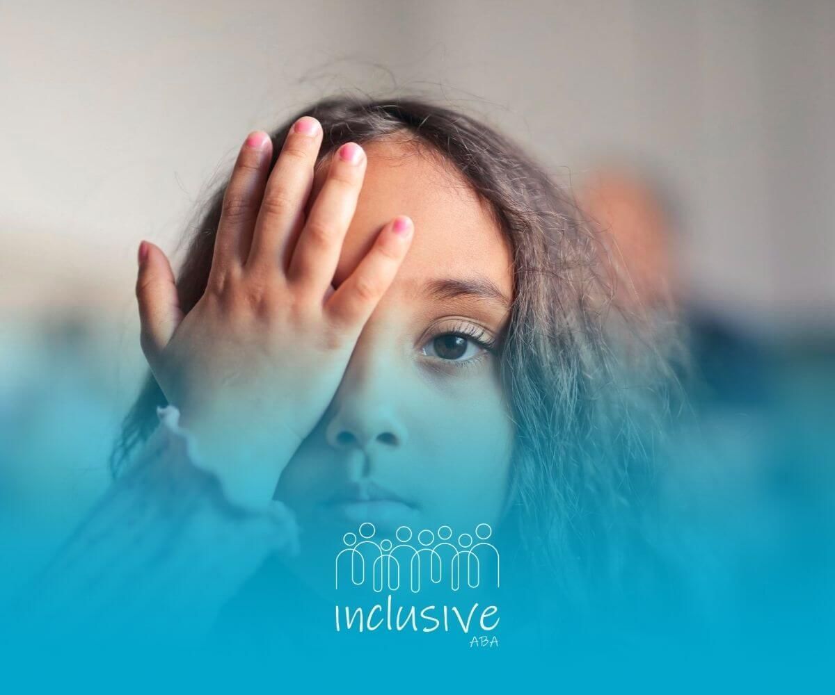 Young girl with autism covering one eye with her hand and looking forward.