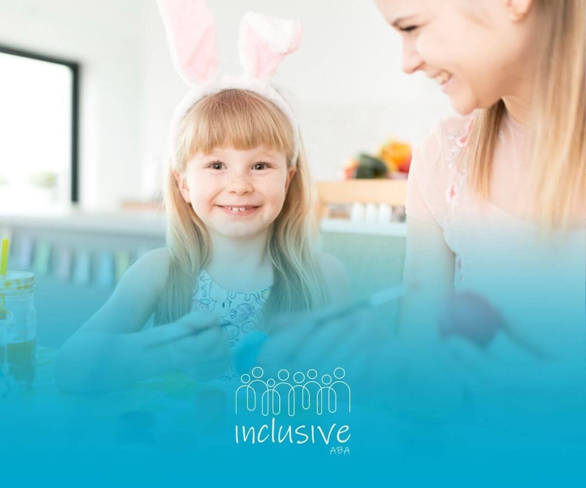 A BCBA and a little girl are sitting at a table painting easter eggs during ABA therapy.