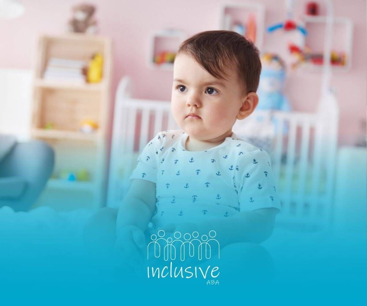 A baby with autism is sitting on a bed in a nursery.
