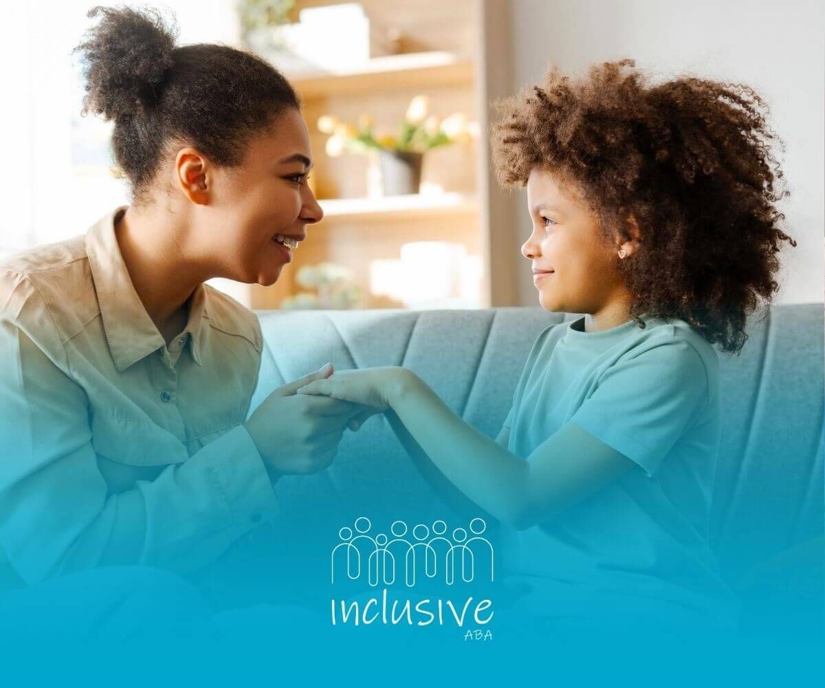 An ABA therapist and a child are sitting on a couch holding hands in ABA therapy.
