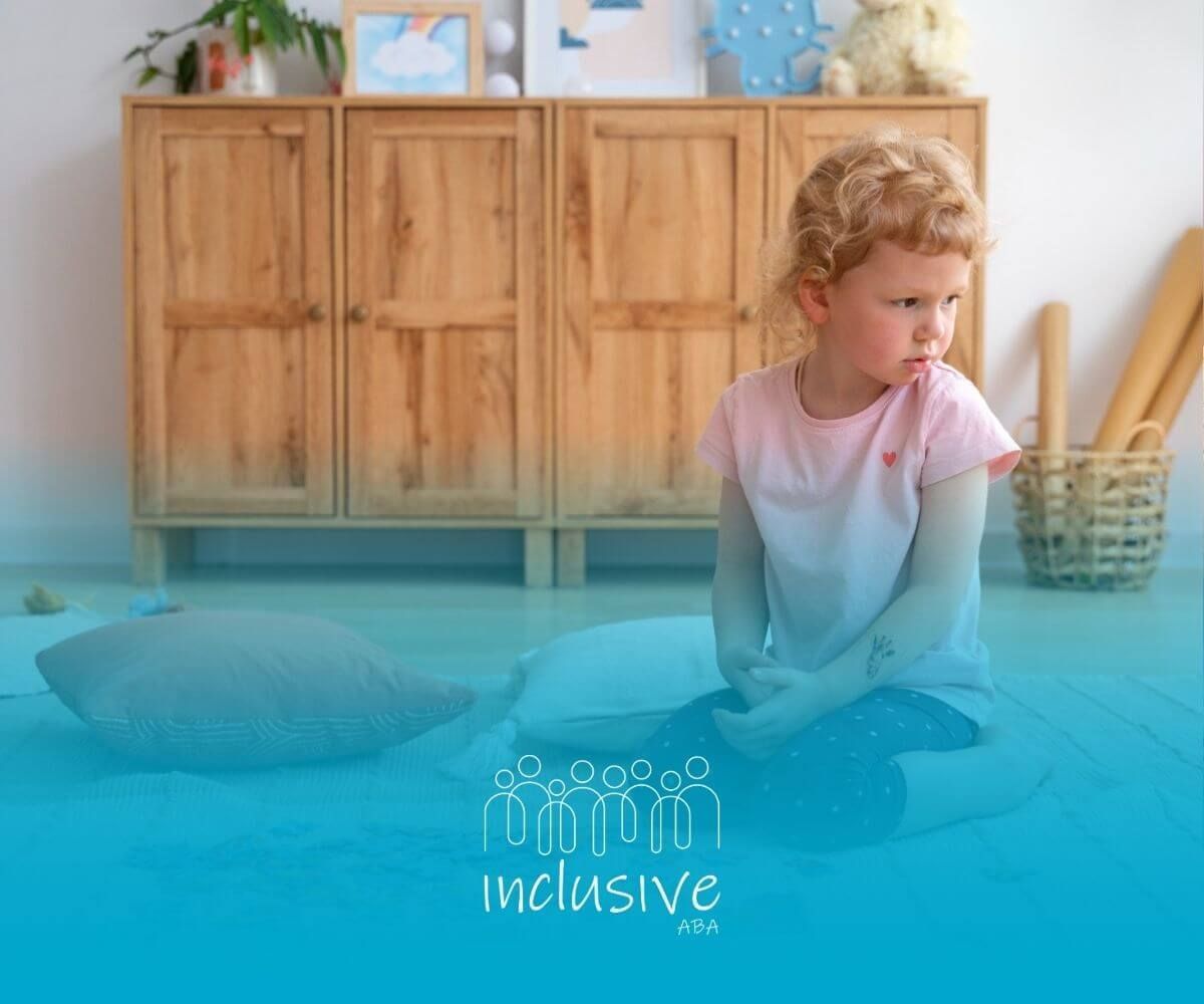 A little girl with autism is sitting on the floor playing with puzzles in ABA therapy.