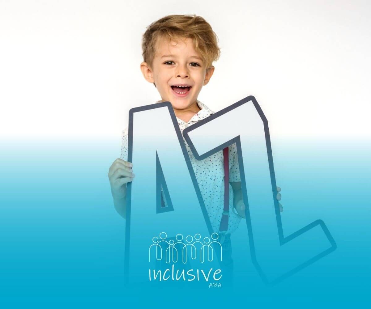 A boy with autism happily holds up the letters 