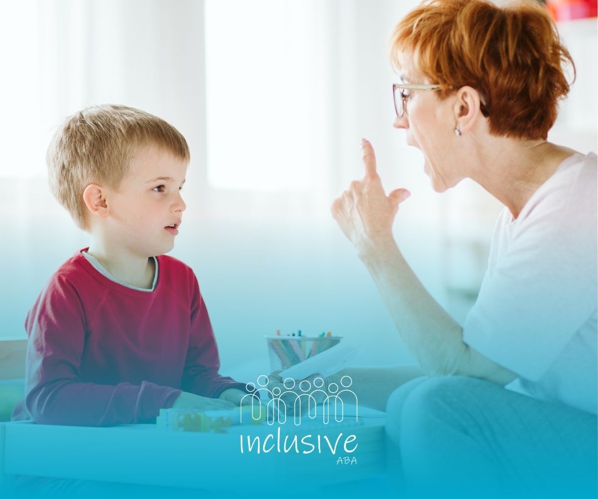 A woman is sitting at a table talking to a young boy.