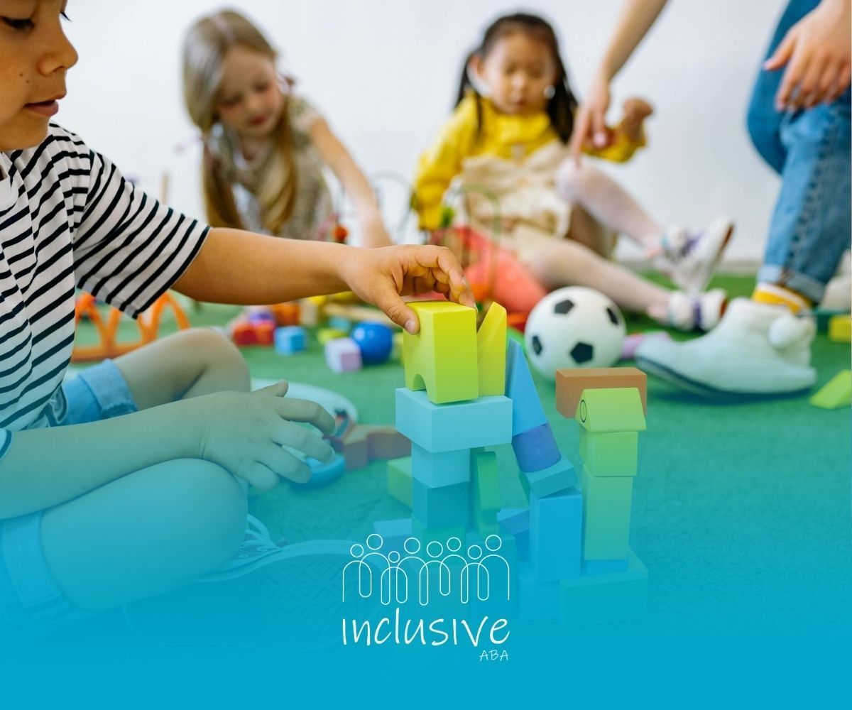 Autistic children playing with building blocks on a green play mat during ABA therapy session in NE.