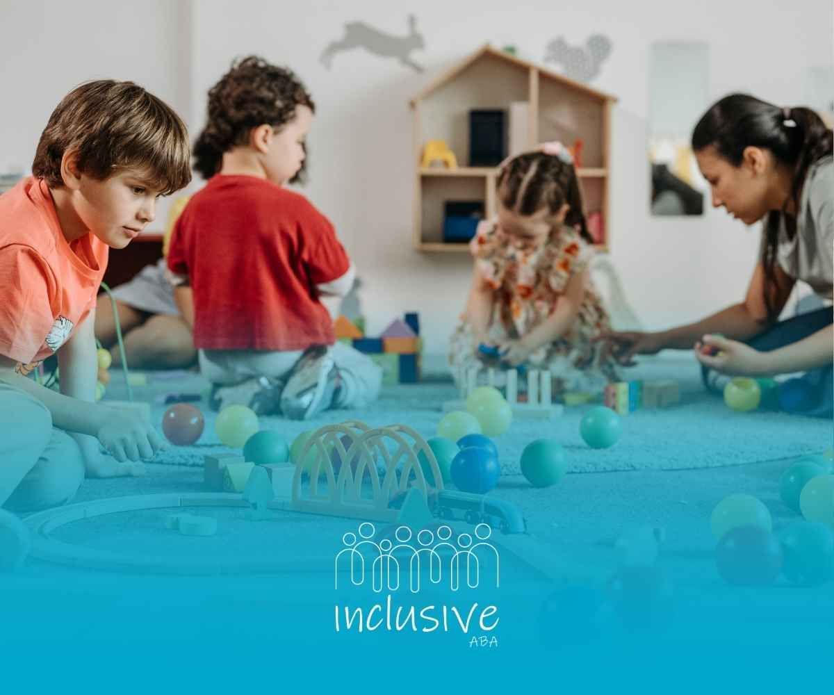 Children playing in a colorful playroom. A boy in a red shirt focuses on a wooden train set.