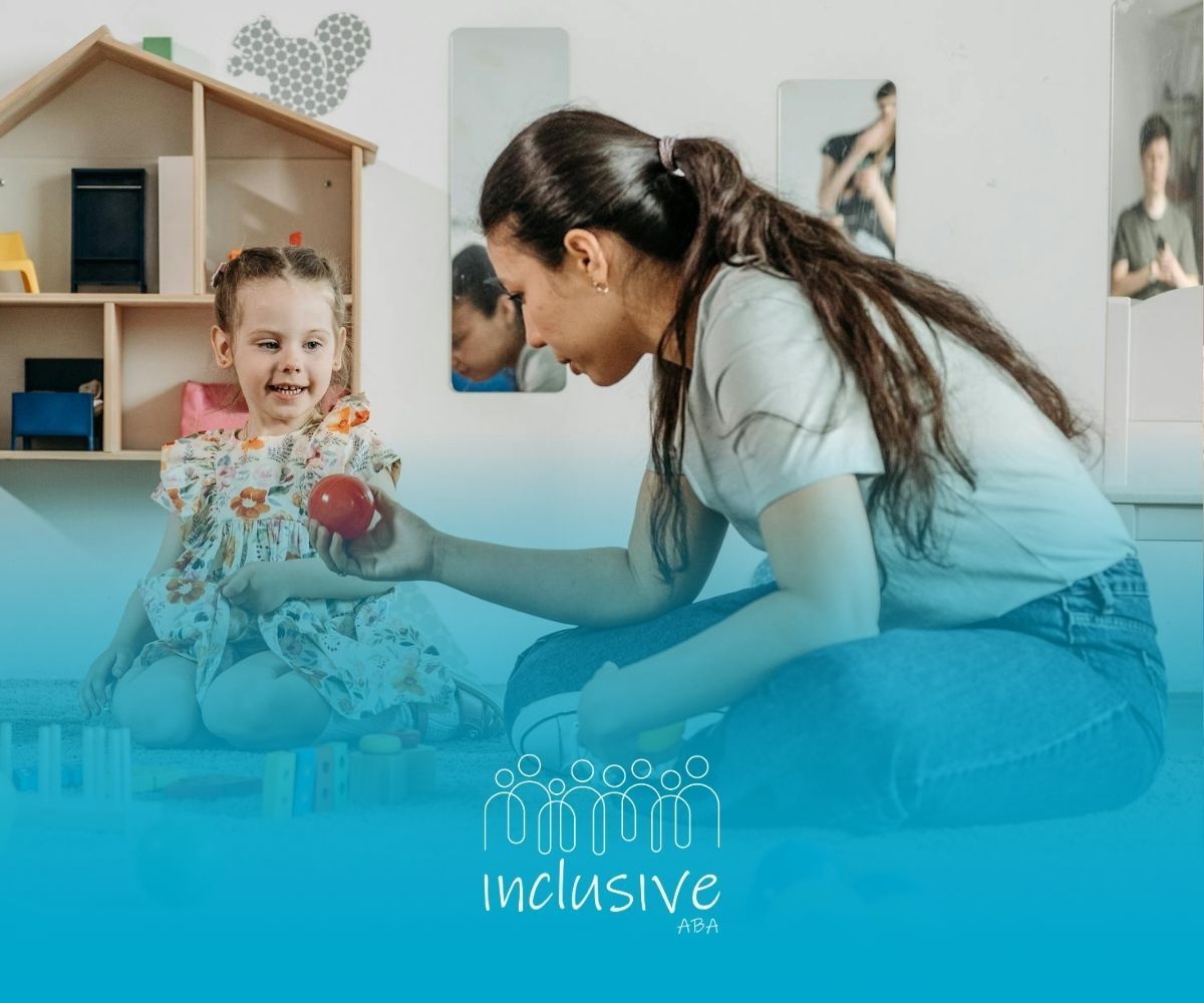 An RBT handing a red ball to a smiling autistic child in a playroom during ABA therapy in Nevada.
