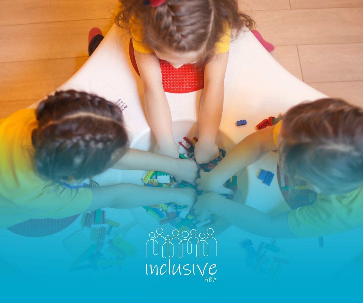 Three children playing with colorful blocks inside a white table.