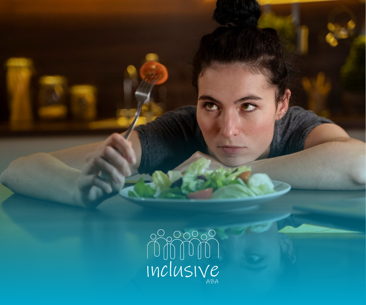 A woman is sitting at a table looking at a plate of food.