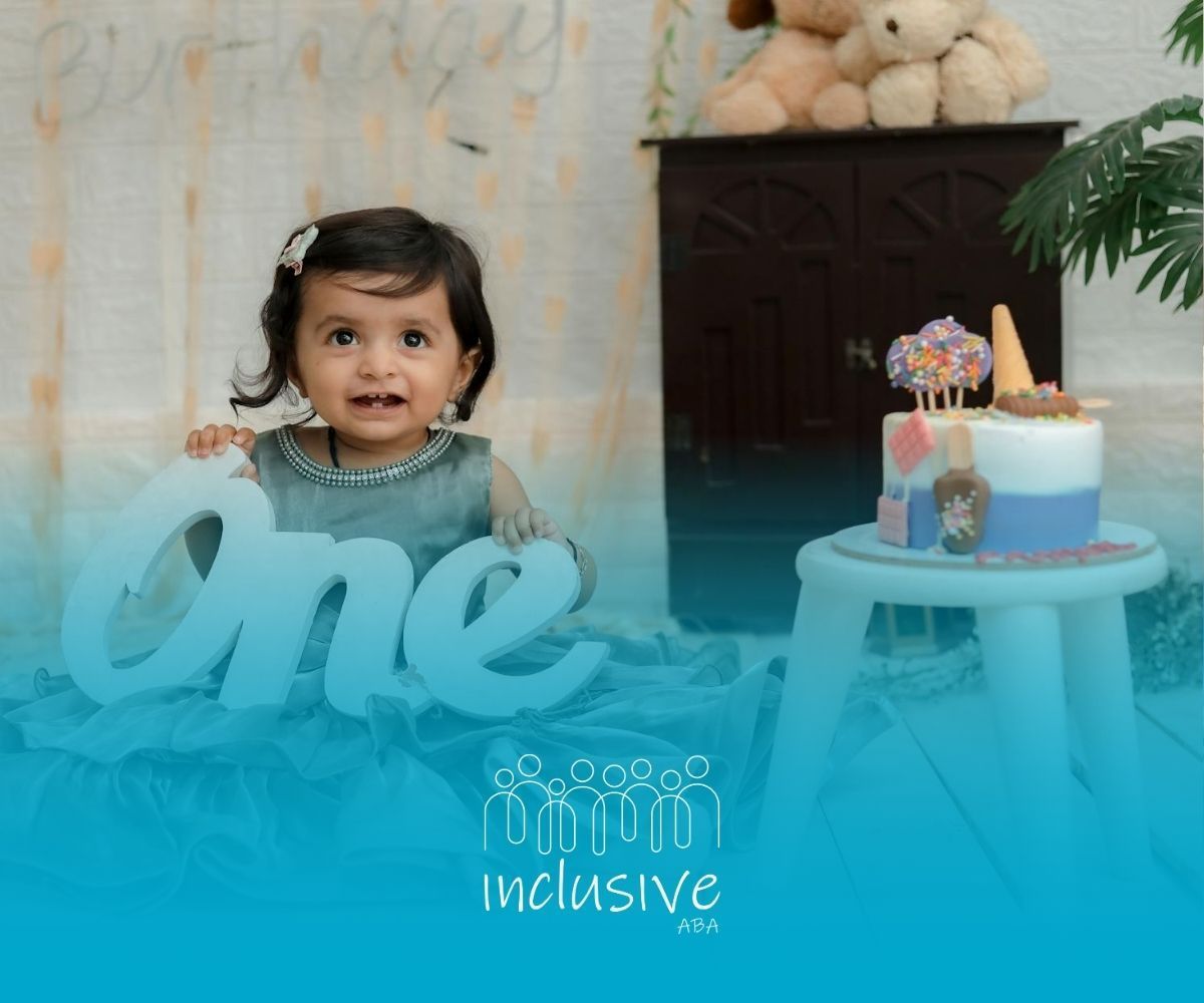 An autistic toddler in a green dress holding a ‘One’ sign at her birthday setup in Nebraska.