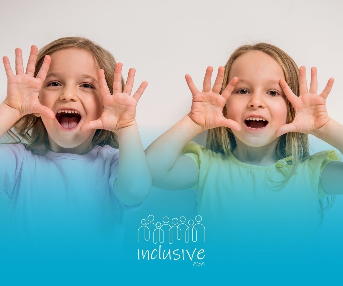 Two young children with open mouths and hands up, smiling, against a white background. 