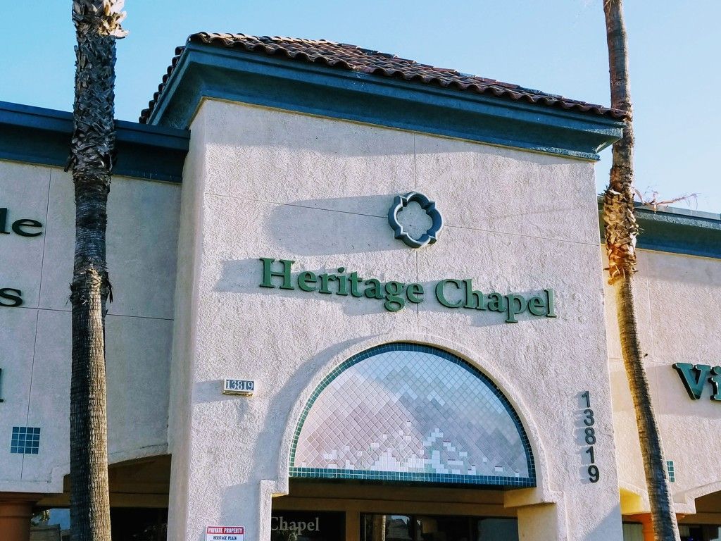 The front of the heritage chapel building with palm trees in front of it