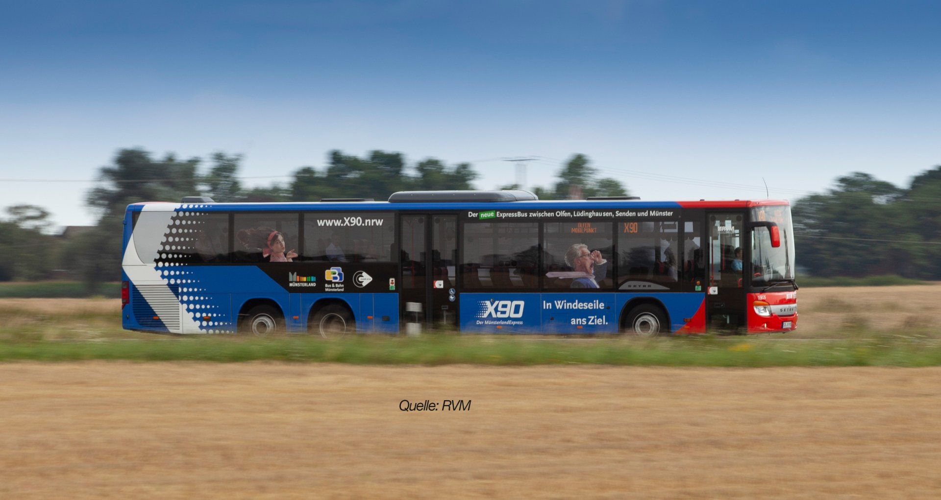 A blue and white bus is driving down a road.