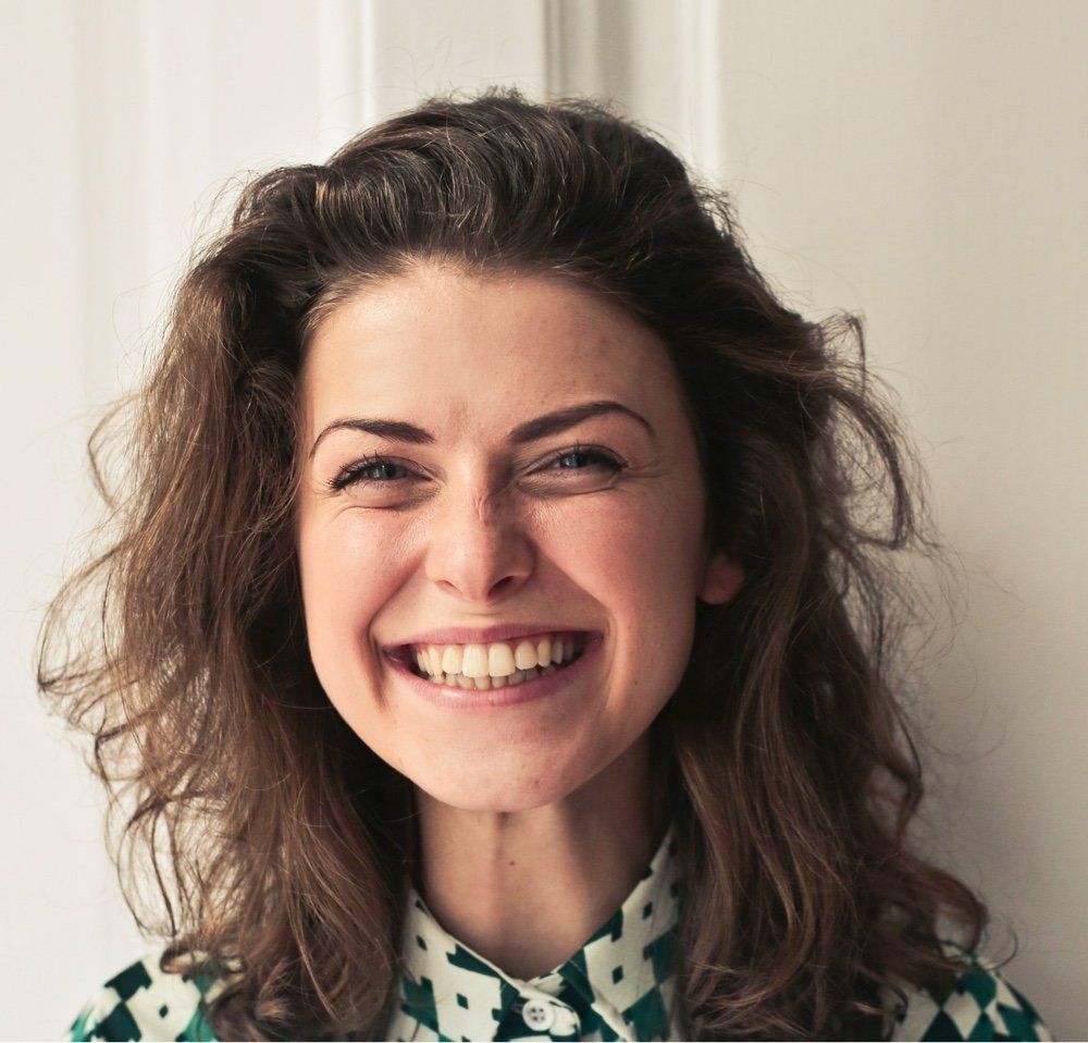 A woman wearing a green and white shirt is smiling